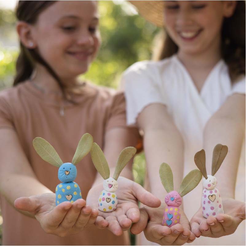 girls holding painted clay bunnies in out stretched arms
