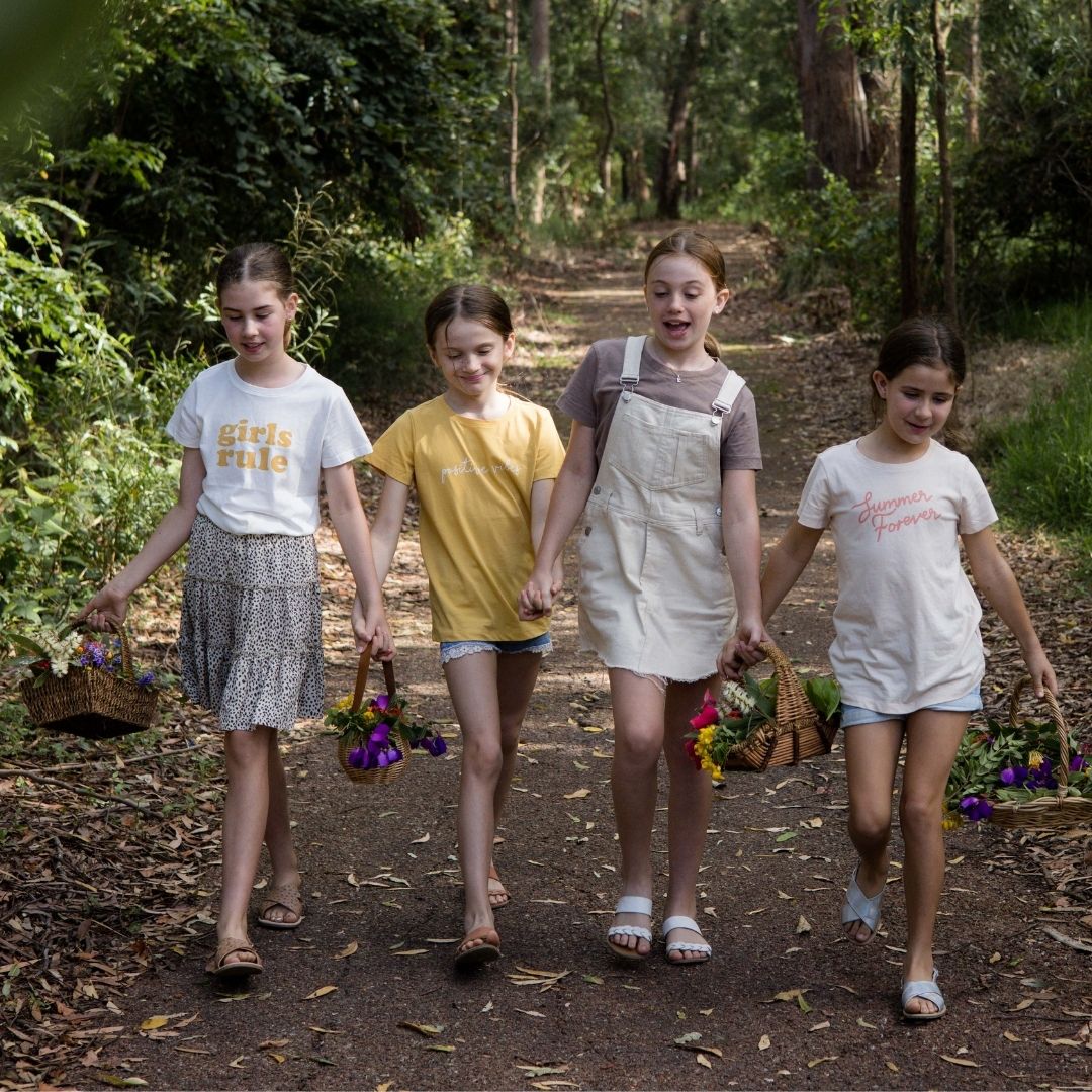 4 girls walking together in forest with basket of flowers